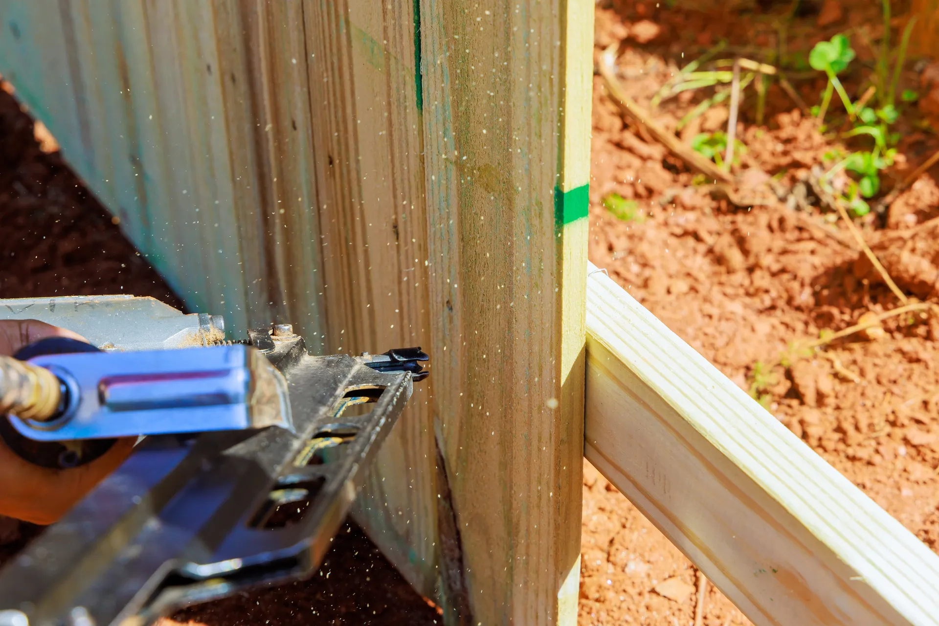 Close-up of fence post installation with drill and metal bracket