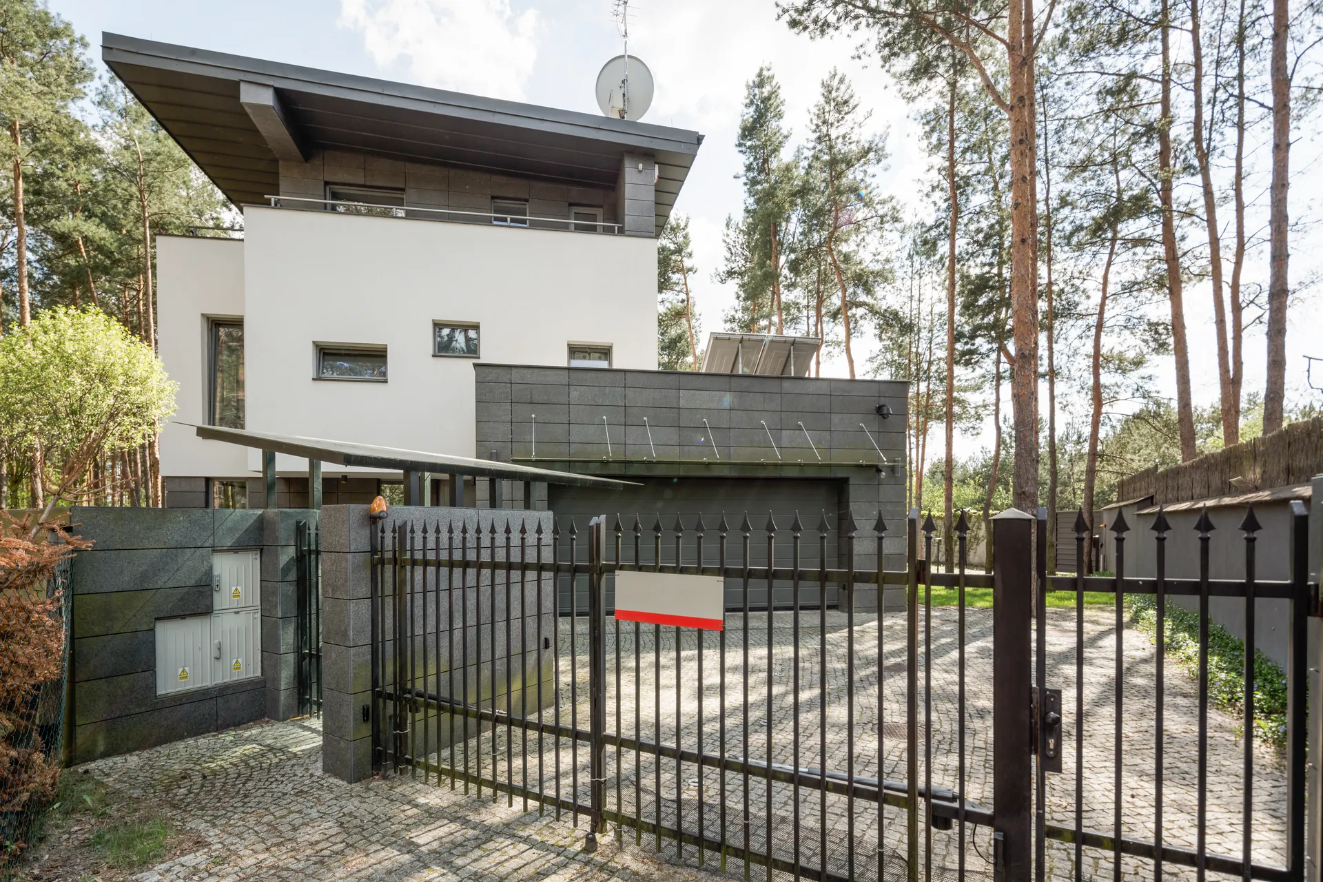 Modern home with black iron driveway gate and security fence