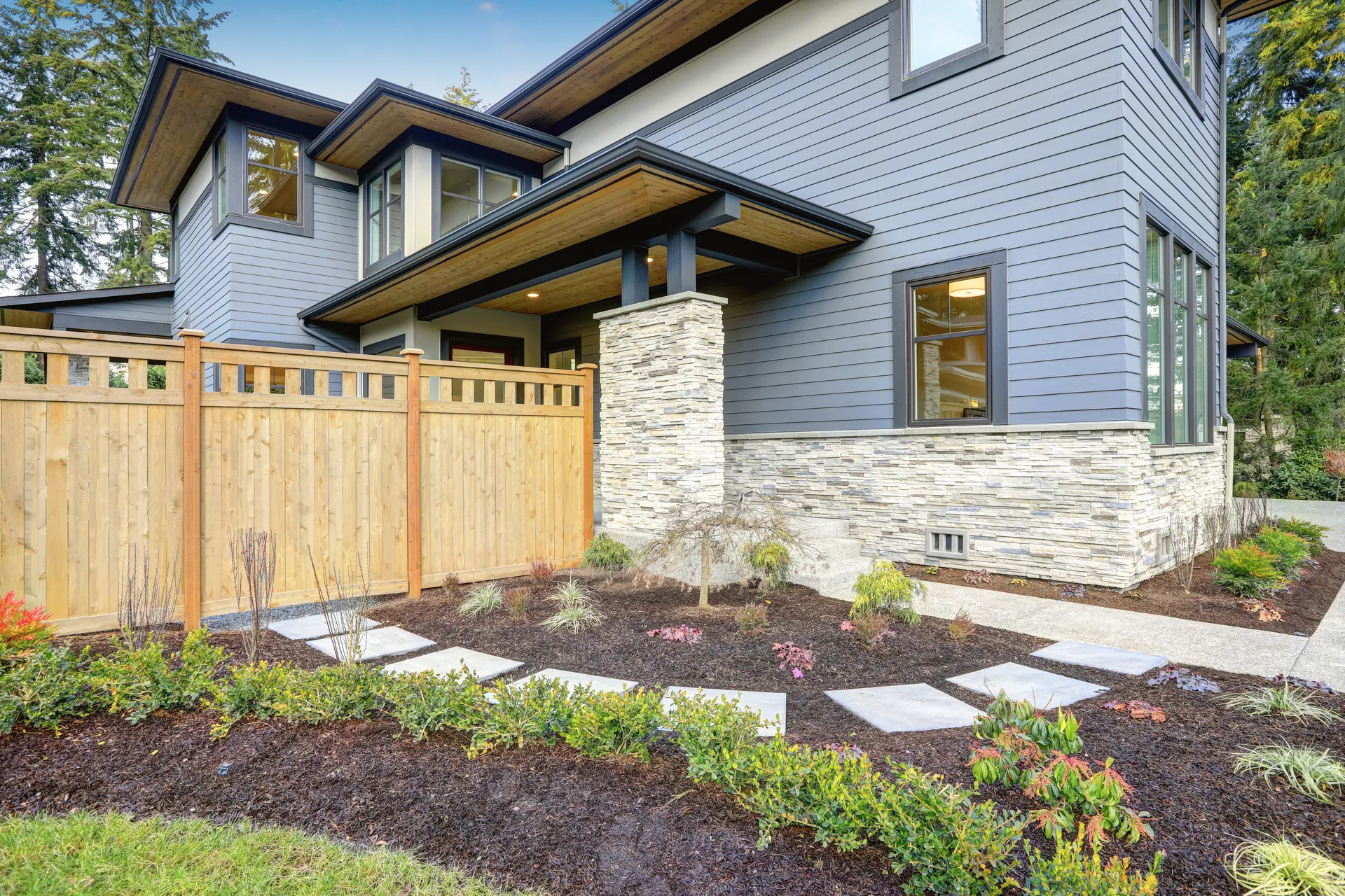 New cedar privacy fence next to a craftsman-style home with landscaping