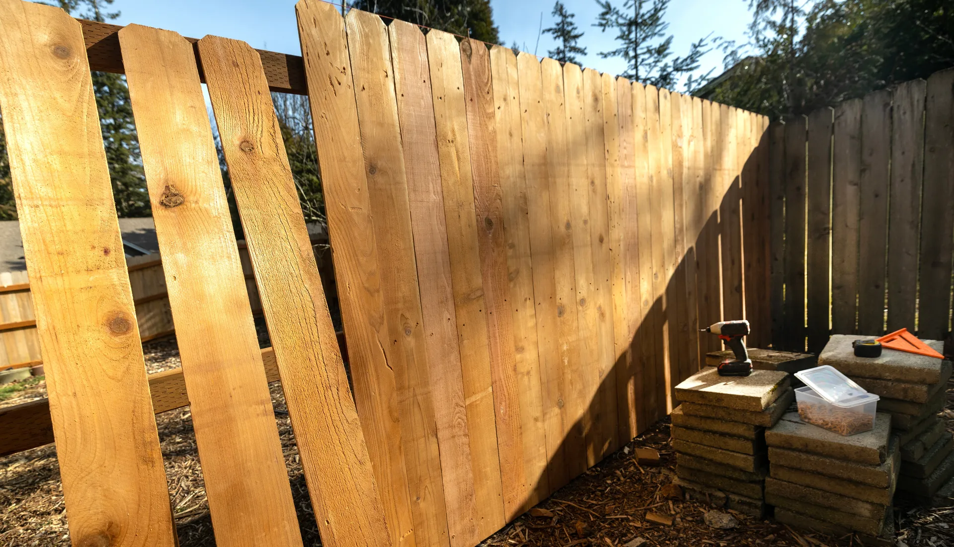 Wood fence repair in progress with new cedar pickets being installed